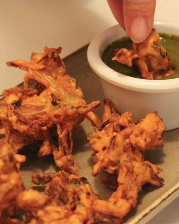Onion bhajis with a pot of green chutney